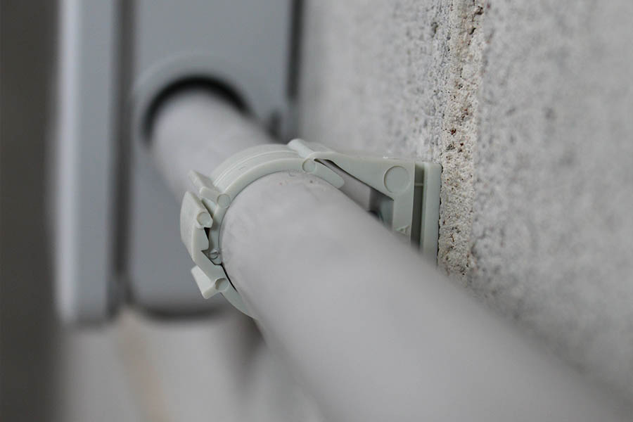 A pipe secured to a wall with the ABT Smart Clamp, an XHA nail, and the FORCE ONE+ nailer